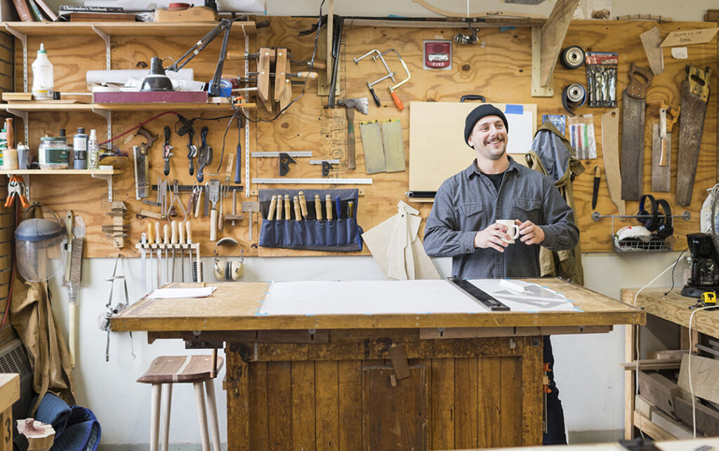 Grant Burger standing at his NBSS bench, holding a mug of coffee and smiling