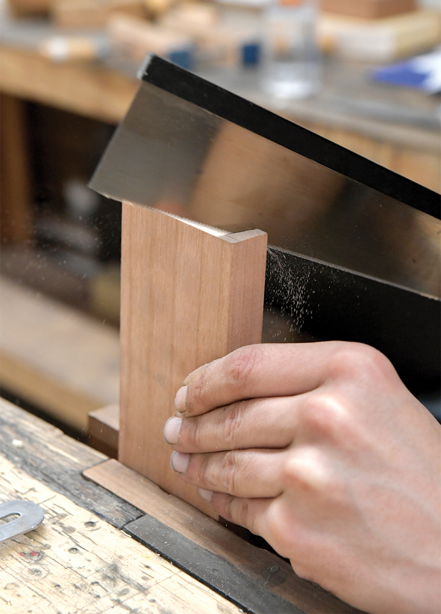 A student cuts wood with a dovetail saw