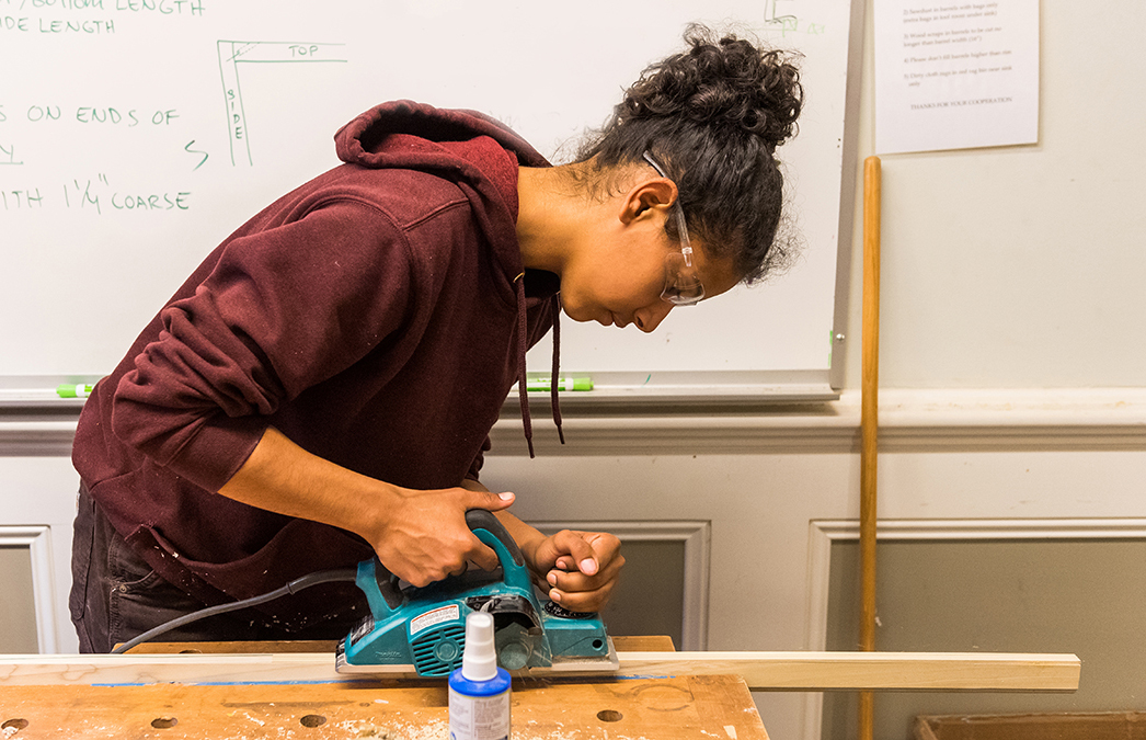 Carpentry student using a power sander