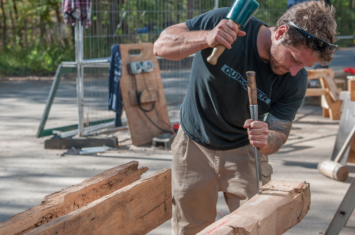 Hollis Webb at work with a chisel on a timber frame beam