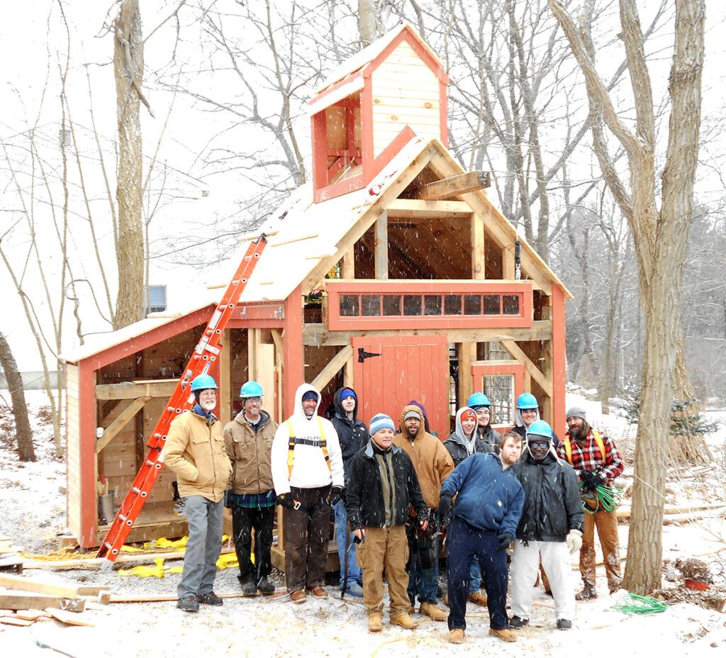 Carpentry class in front of shack in construction, in the snow