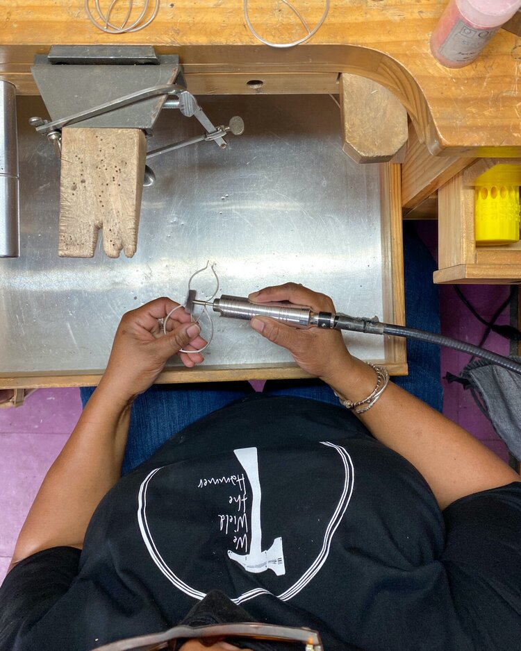 Karen working at her bench wearing a We Wield the Hammer shirt