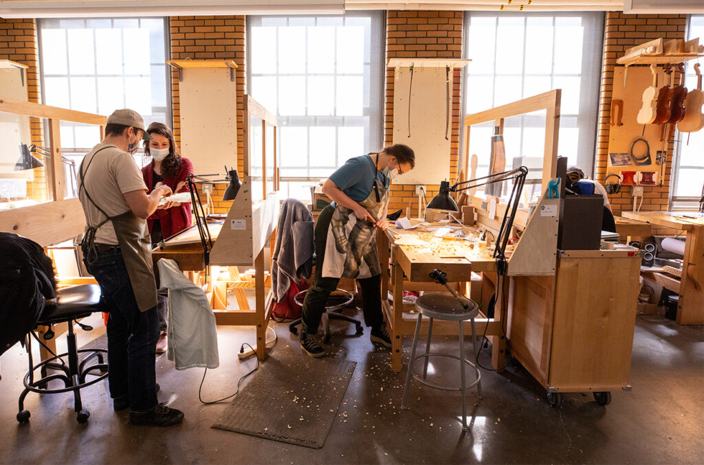 Nathan (left) working with a student in the Violin Making & Repair space.