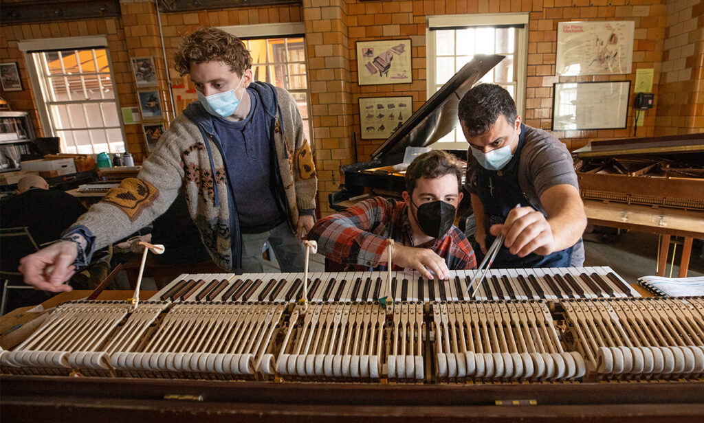 Teaching Assistant Will Roper (center) working with Piano Technology students