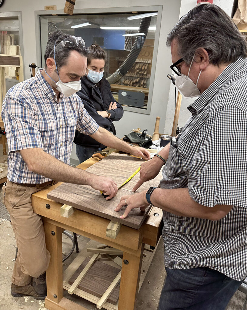 Nick helping a student measure a top for a Shaker table