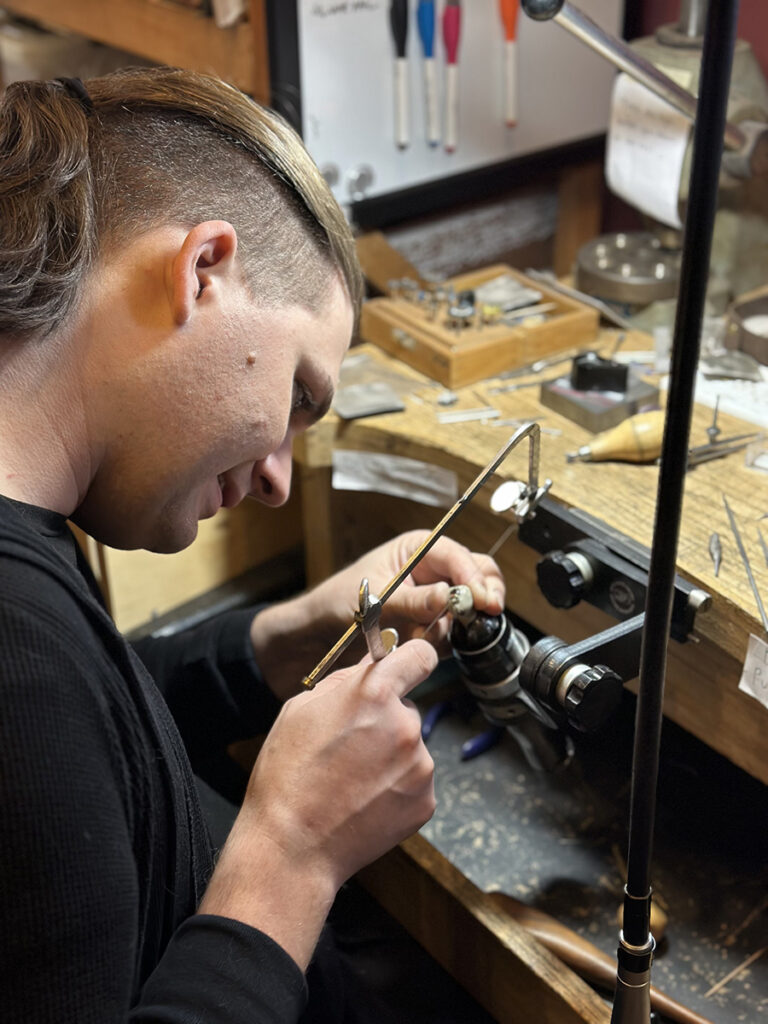 Jaime Goodhue sawing at their bench