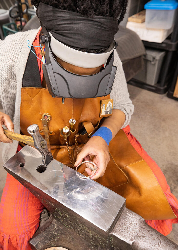 Jewelry Making student hammering a bracelet at an anvil