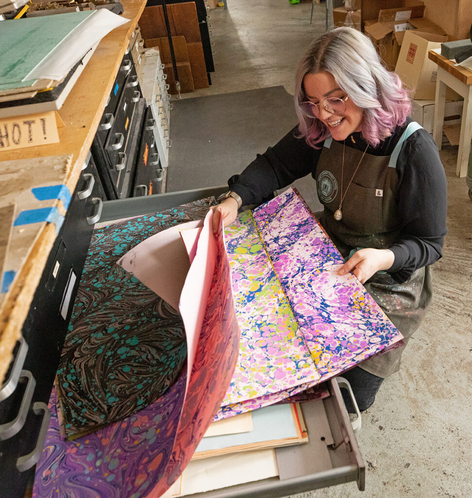Abra looking through marbled papers that she made