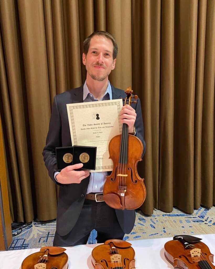 Justin Hess holds award winning violin and certificate at the 2022 VSA competition