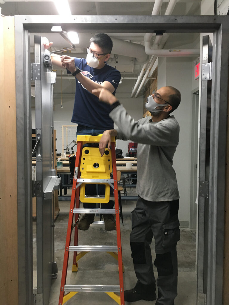 Two locksmithing students working on a door closer