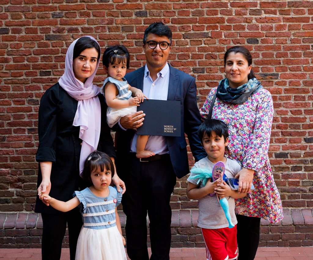 Wali holding his diploma with his family at graduation