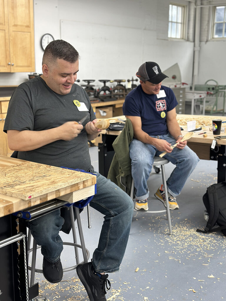 Two students carve spoons in an NBSS workshop for veterans