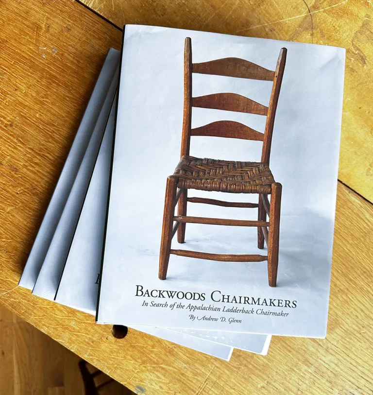 Andy's books stacked in a pile, with the title "Backwoods Chairmakers" and an image of a ladderback chair on the cover