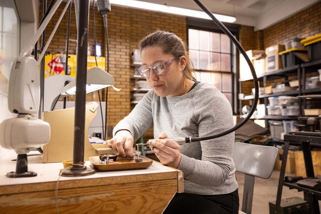 Jewelry making student using a sanding tool