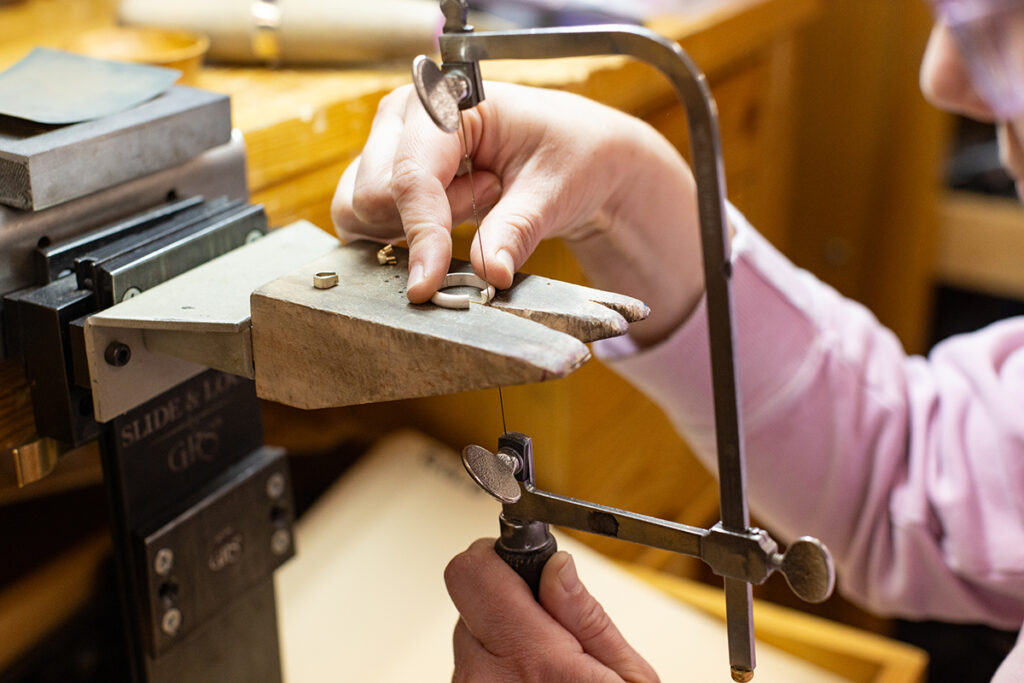 Jeweler cutting a round ring with a saw at a jeweler's bench