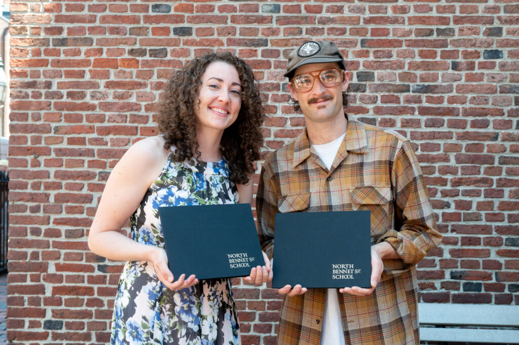 Two graduates holding their diplomas