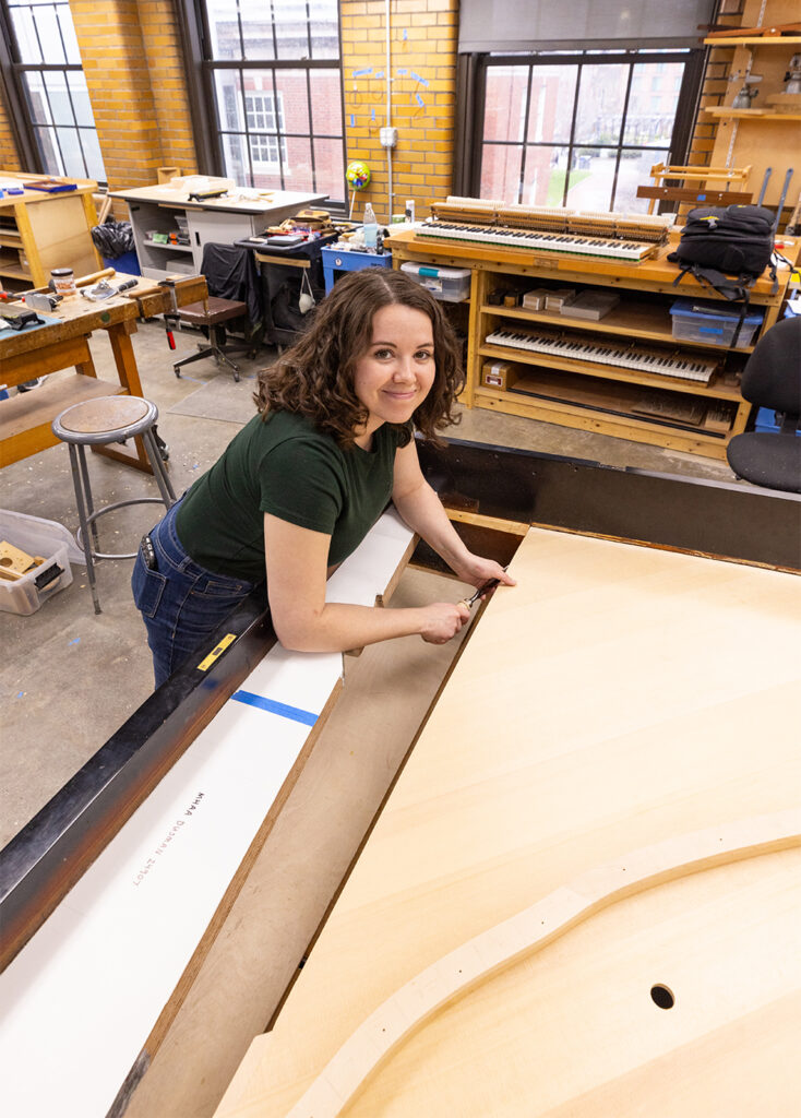 Sydney working on the soundboard of a grand piano as an Advanced student
