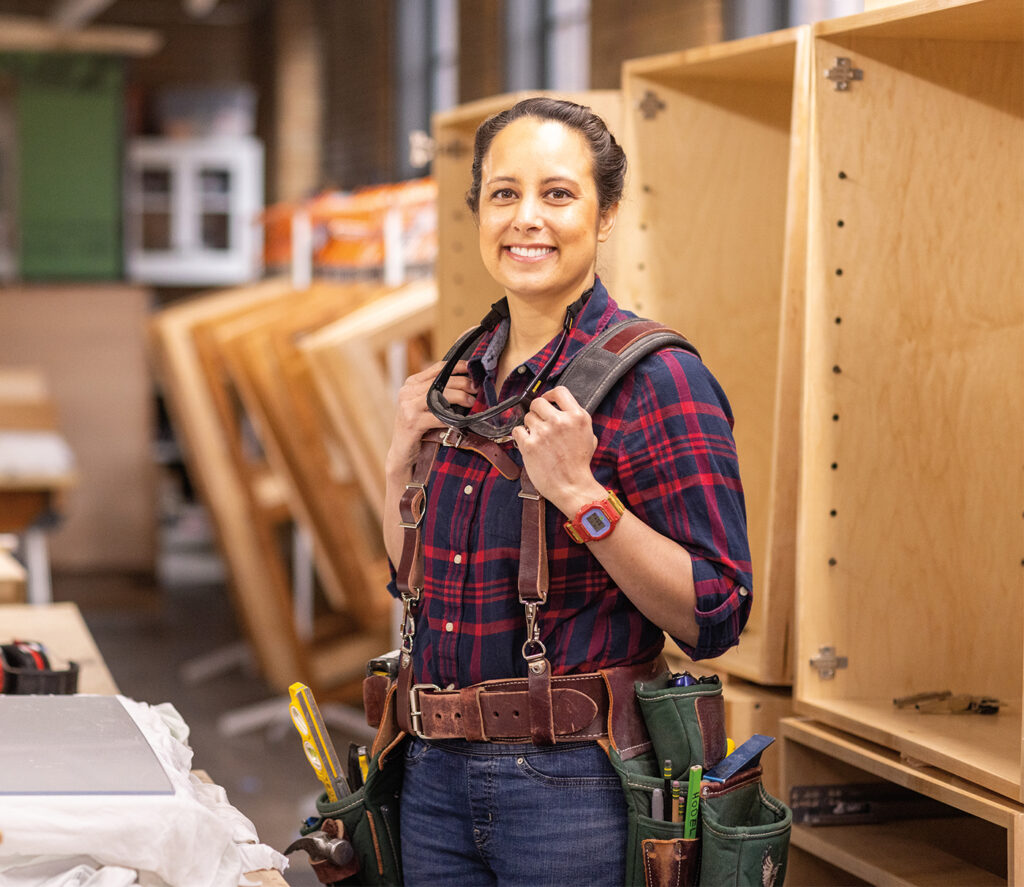 Christina standing in the Carpentry program wearing a tool belt