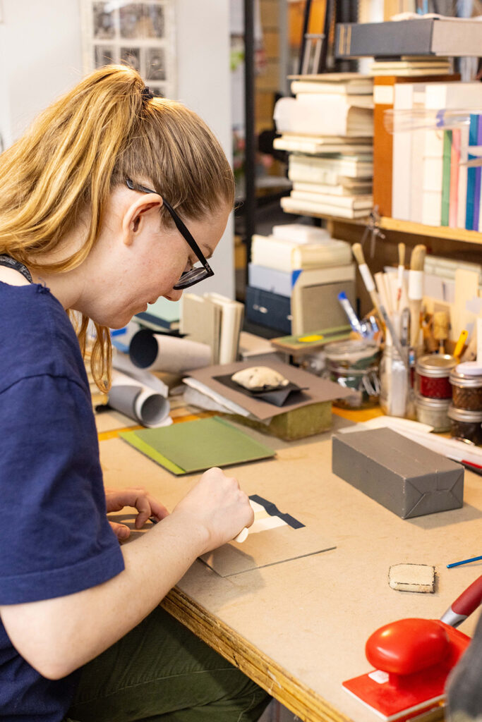 Bookbinding student working on a book spine at her bench