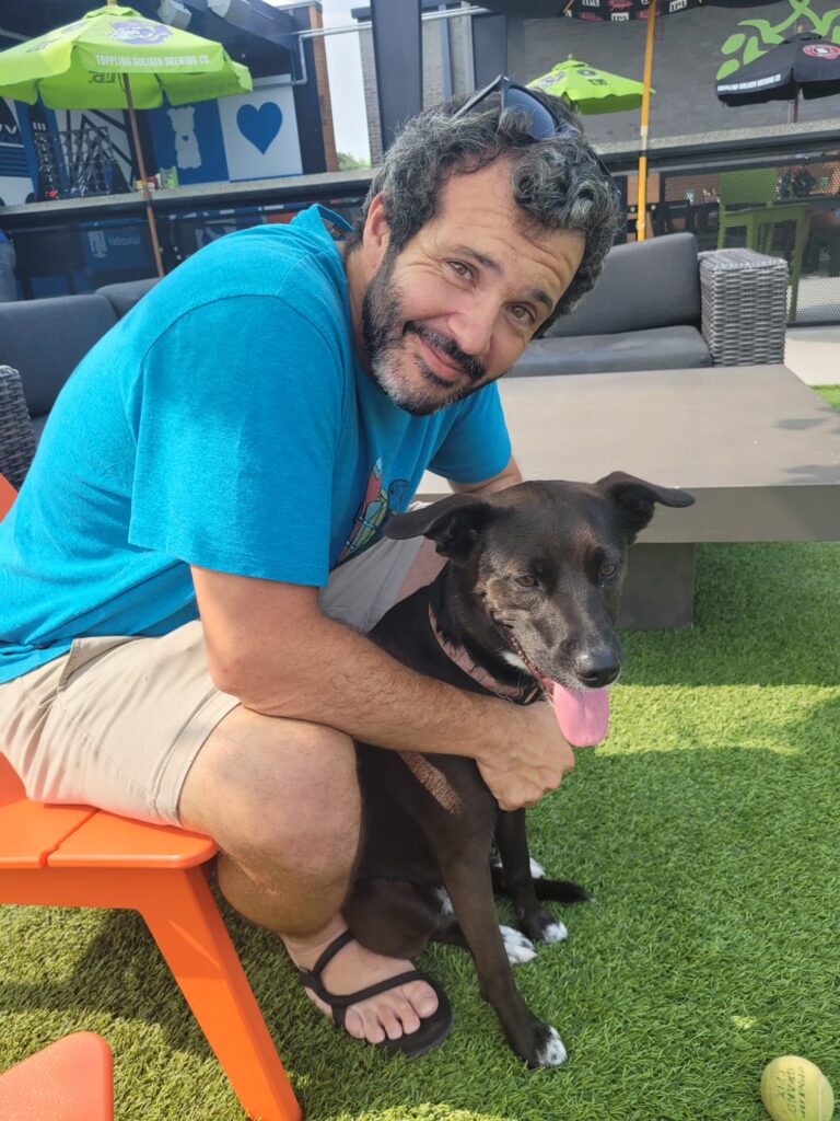 Cyle Thomas, sitting in a chair and holding his dog