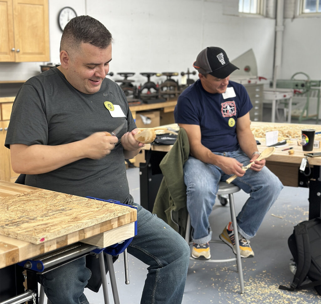 Two veterans carving spoons