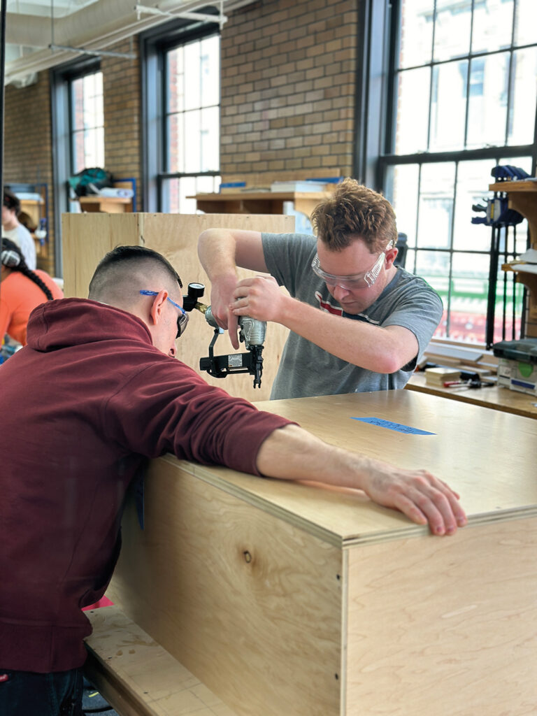 Two Carpentry students drilling the boxes together