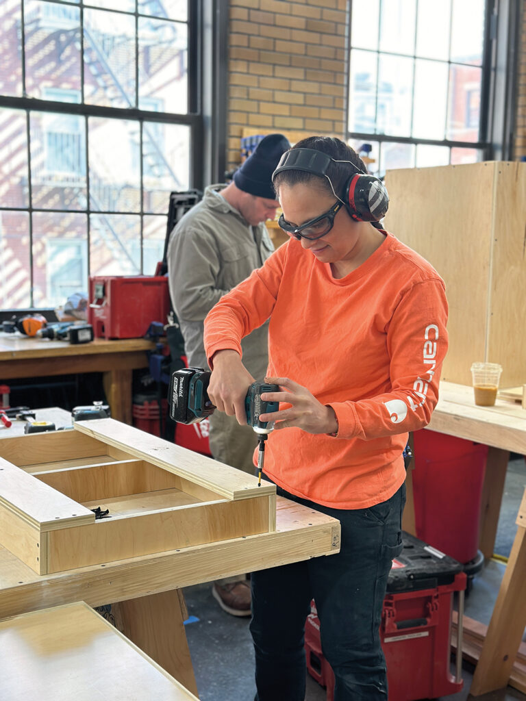 Carpentry student drilling part of the cabinets