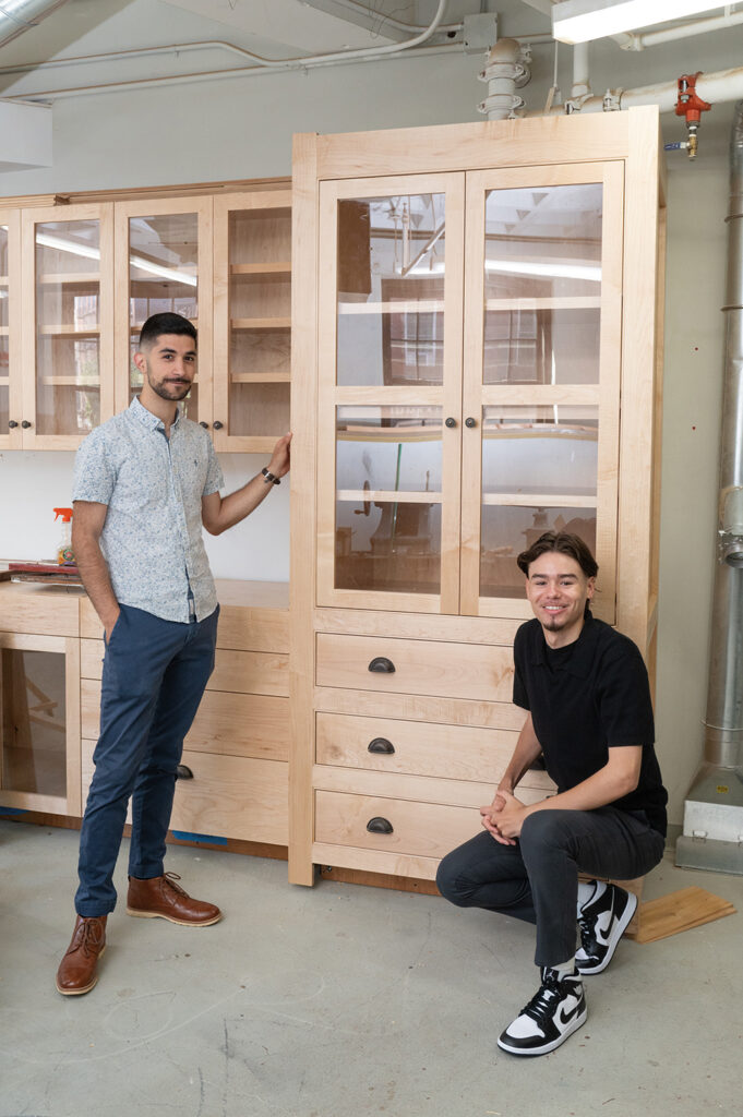 Cal and Omar pose by the completed Preservation Carpentry cabinets