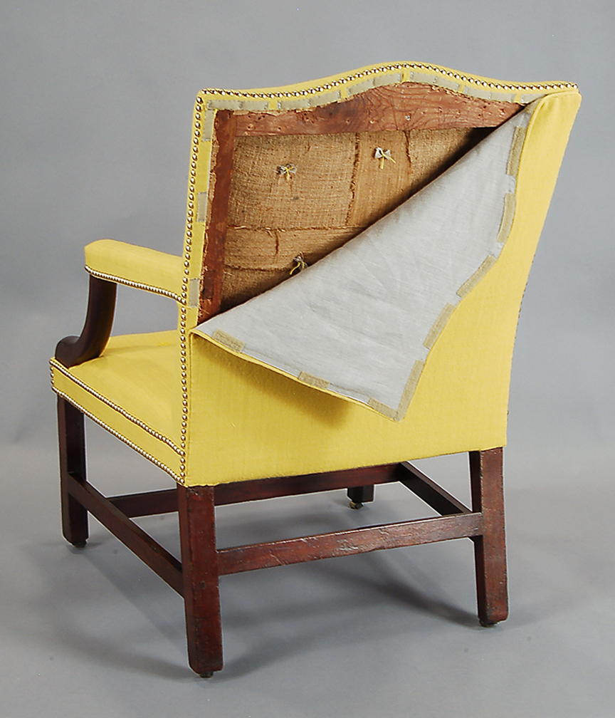 Arm chair with yellow upholstery fabric coming away from the back of the chair