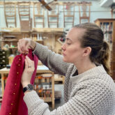 Carolyn pinning red upholstery fabric to a chair frame