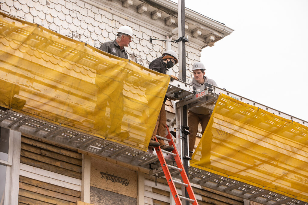 Preservation Carpentry faculty and students working on the upper story of Memorial Hall, standing on staging