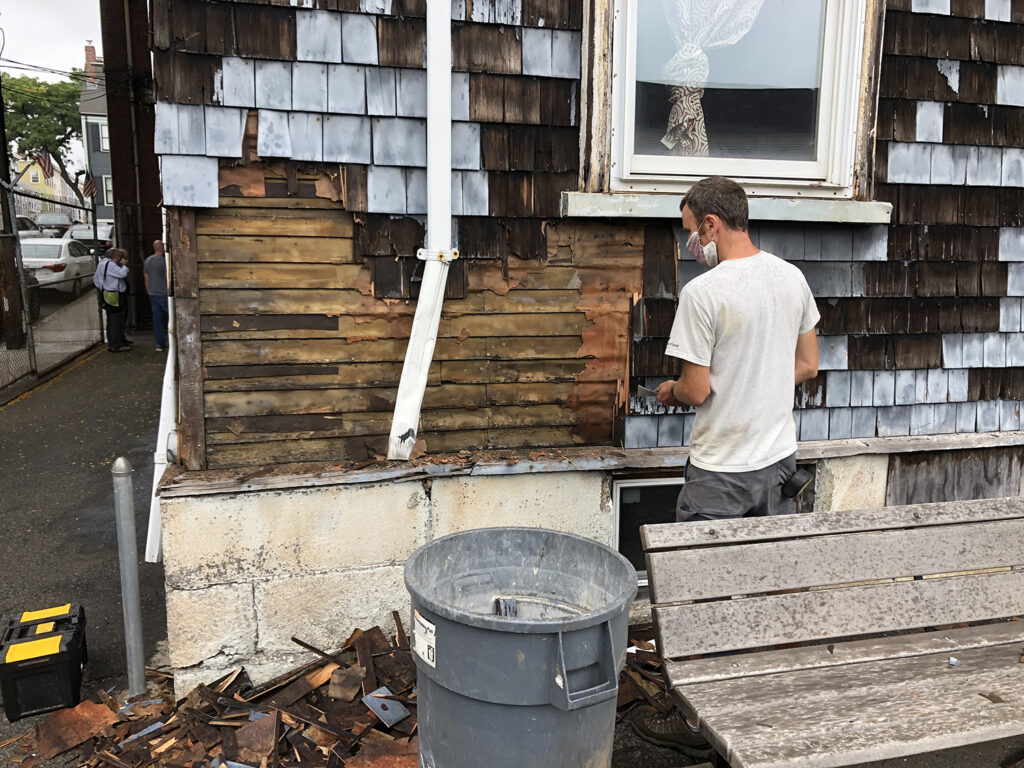 Student Tim Fries inspecting the siding and clapboards in spring 2020