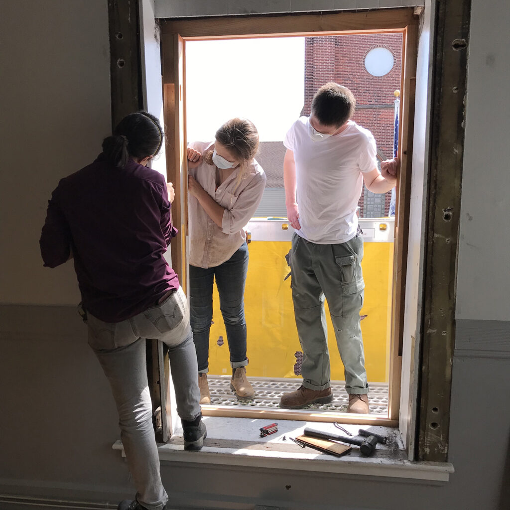 Second-year students Sophie, Charlotte, and Henry inspecting the interior windows in spring 2021