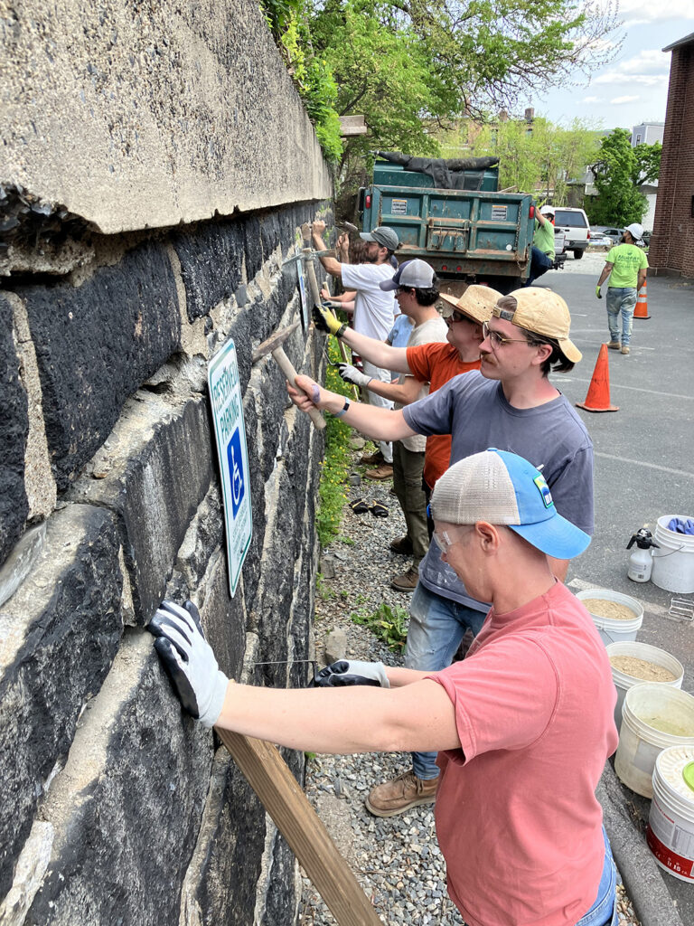 Second-year PC students repointing the stone wall in spring 2023