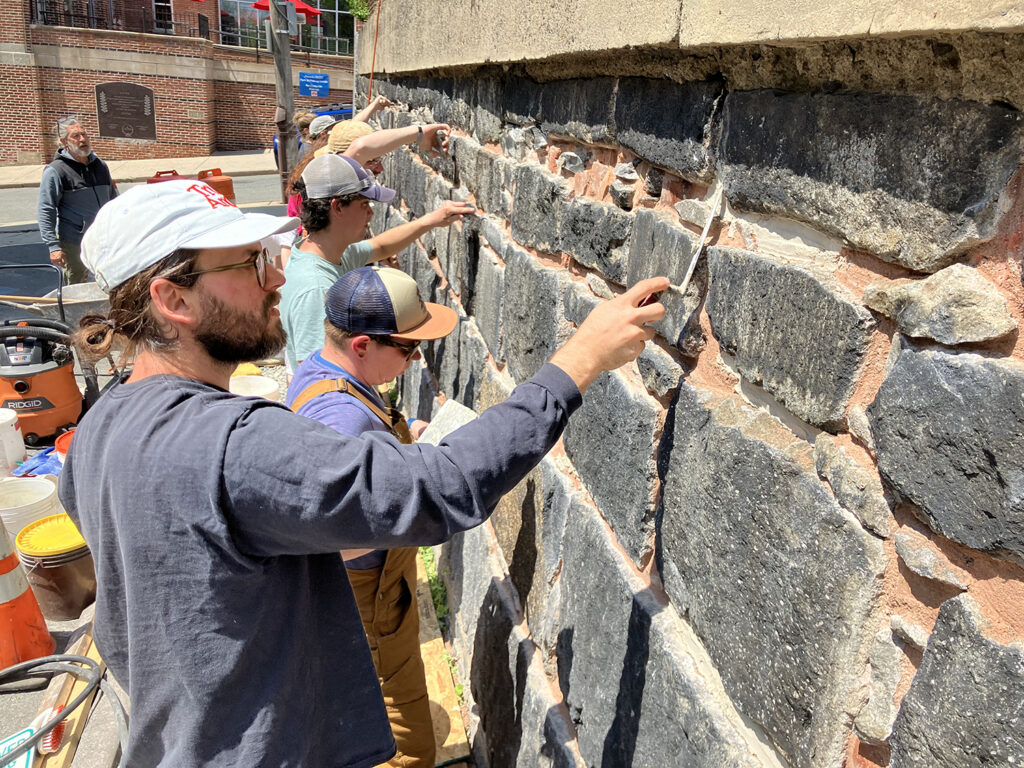 Second-year PC students repointing the stone wall in spring 2023