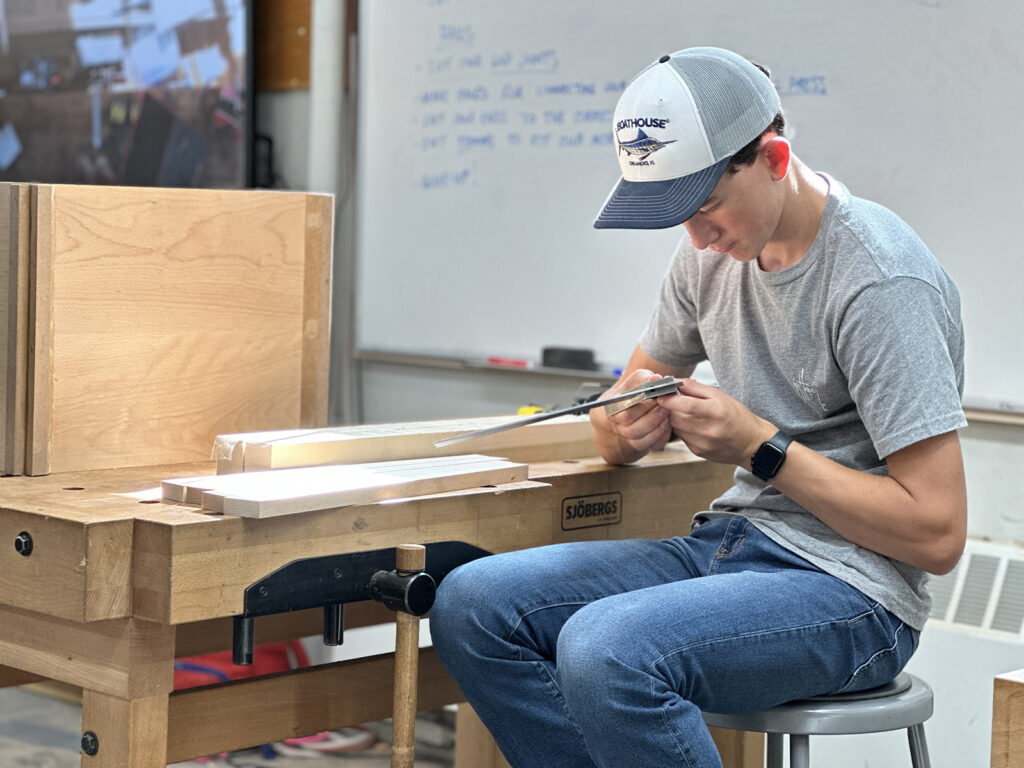 Woodworking Teen Intensive student measuring with a combination square