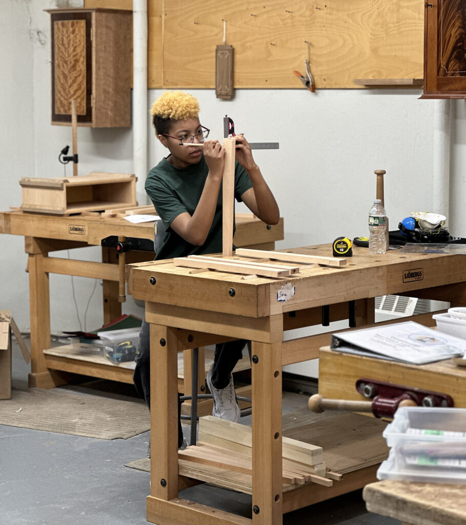 Woodworking Teen Intensive student measuring with a combination square