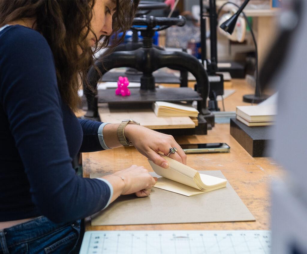Bookbinding student folding paper book signatures