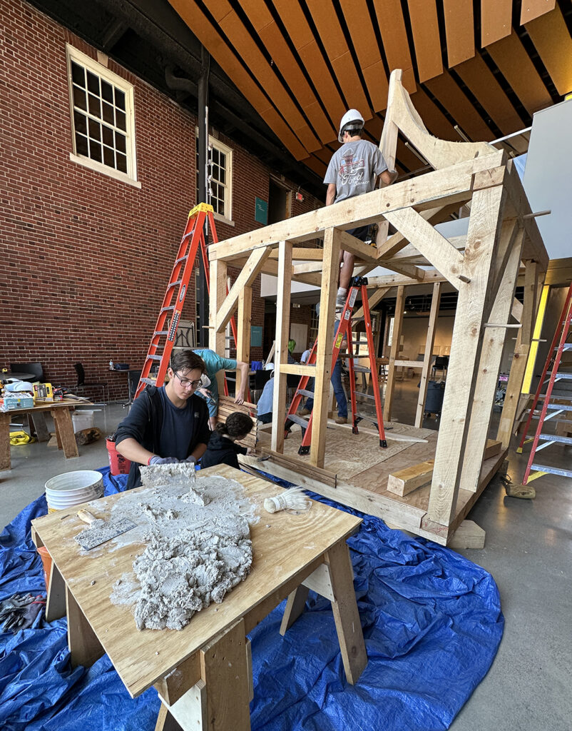 Preservation Intensive students work on their timber frame while Peter (front) mixes hair lime plaster