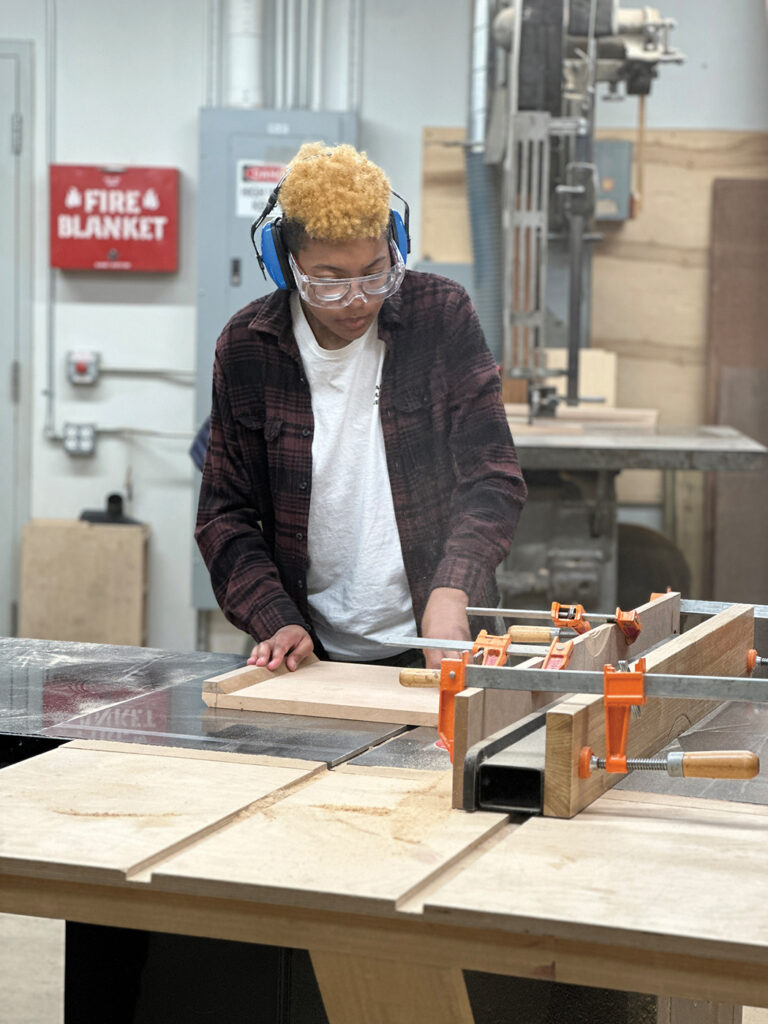Woodworking intensive student Gabby uses the table saw