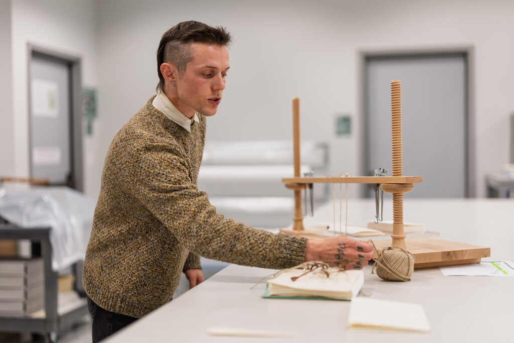 Mitchel Gundrum using a sewing frame at the Huntington Library