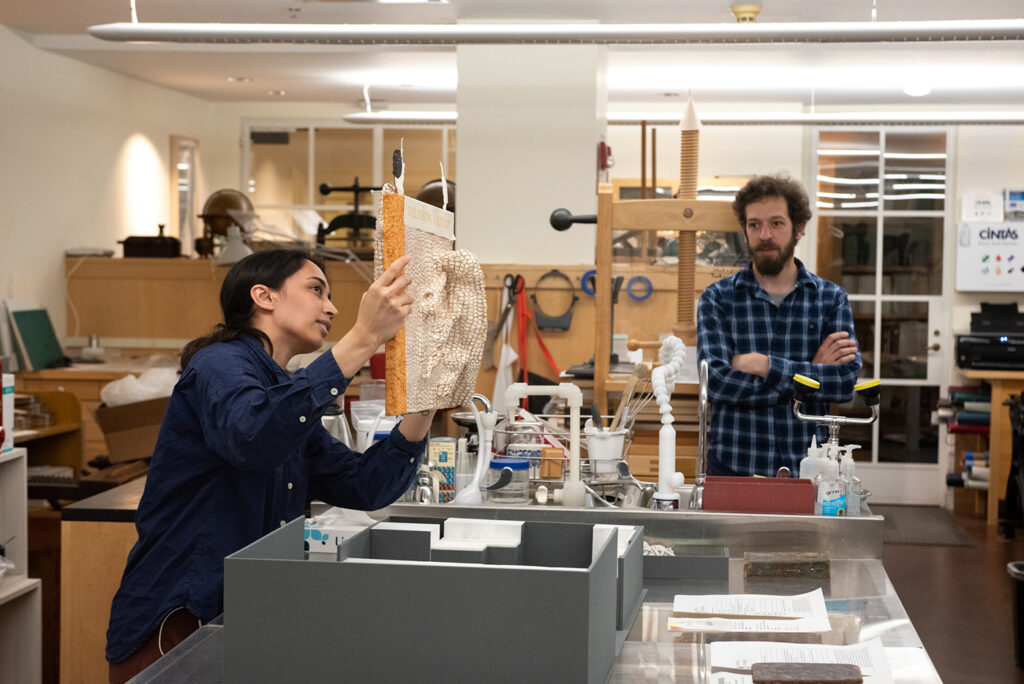Former fellow India Patel showing an object to visitors to the lab with Senior Conservator Graham Patten.